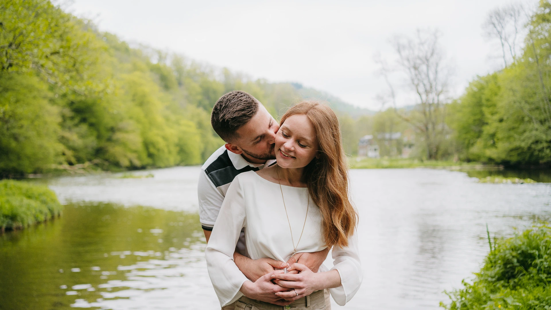 Un couple s'embrassant devant une rivière.