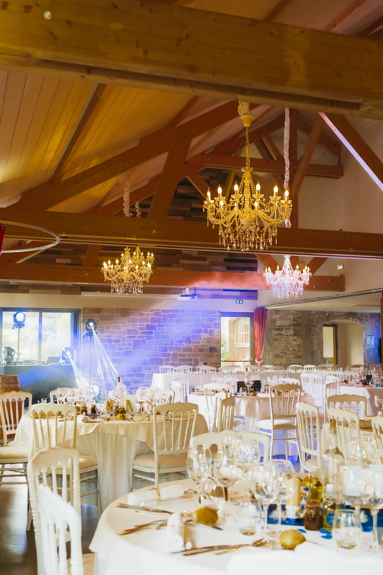 La salle de réception de mariage du Château du Risdoux avec des tables et des chaises blanches.