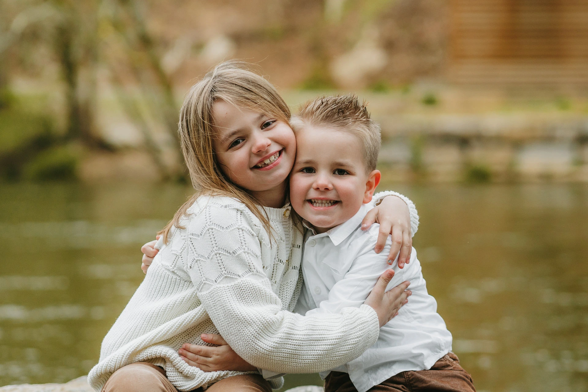 Deux enfants s'enlaçant devant un étang.