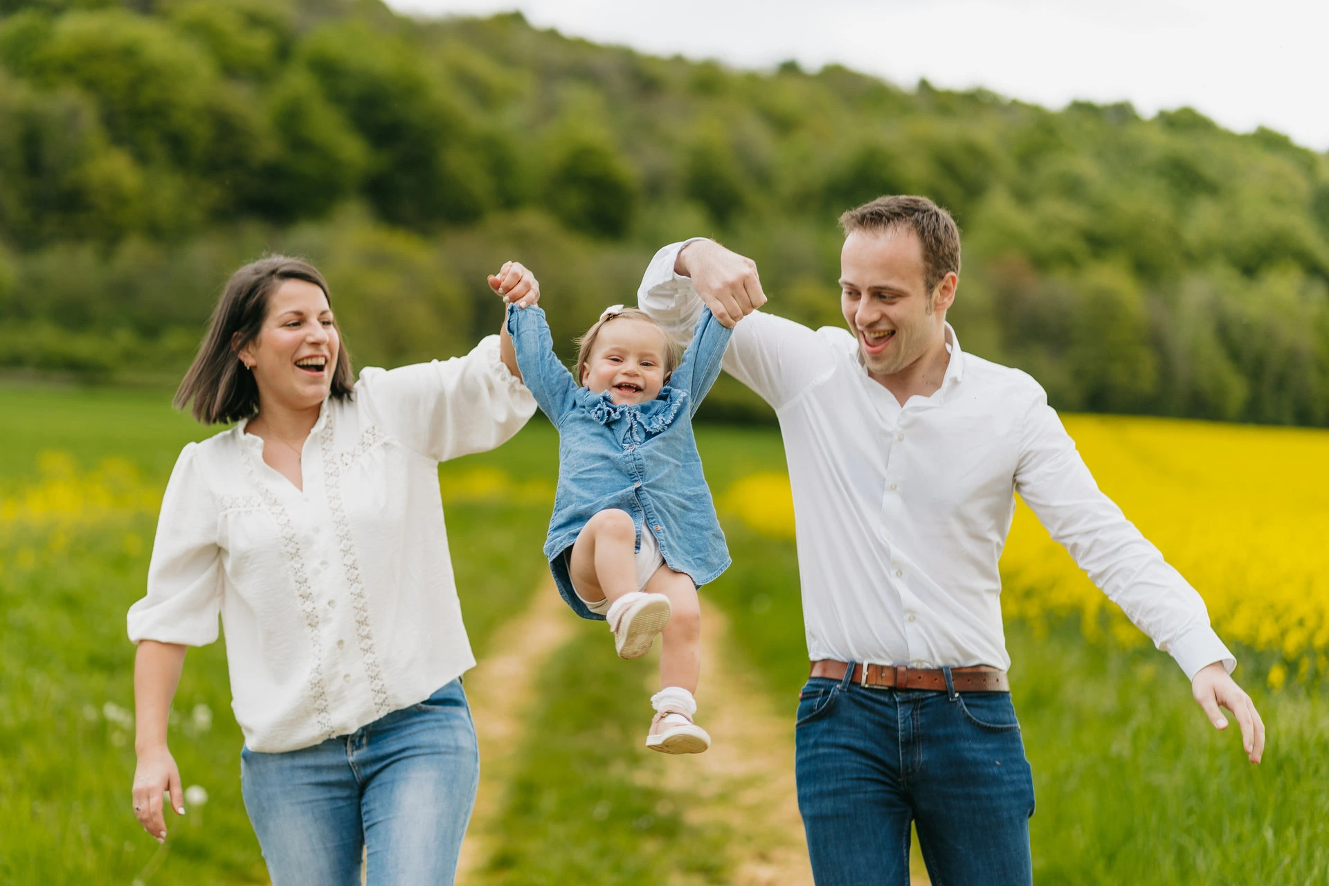Une famille court dans un champ avec un bébé dans les bras.