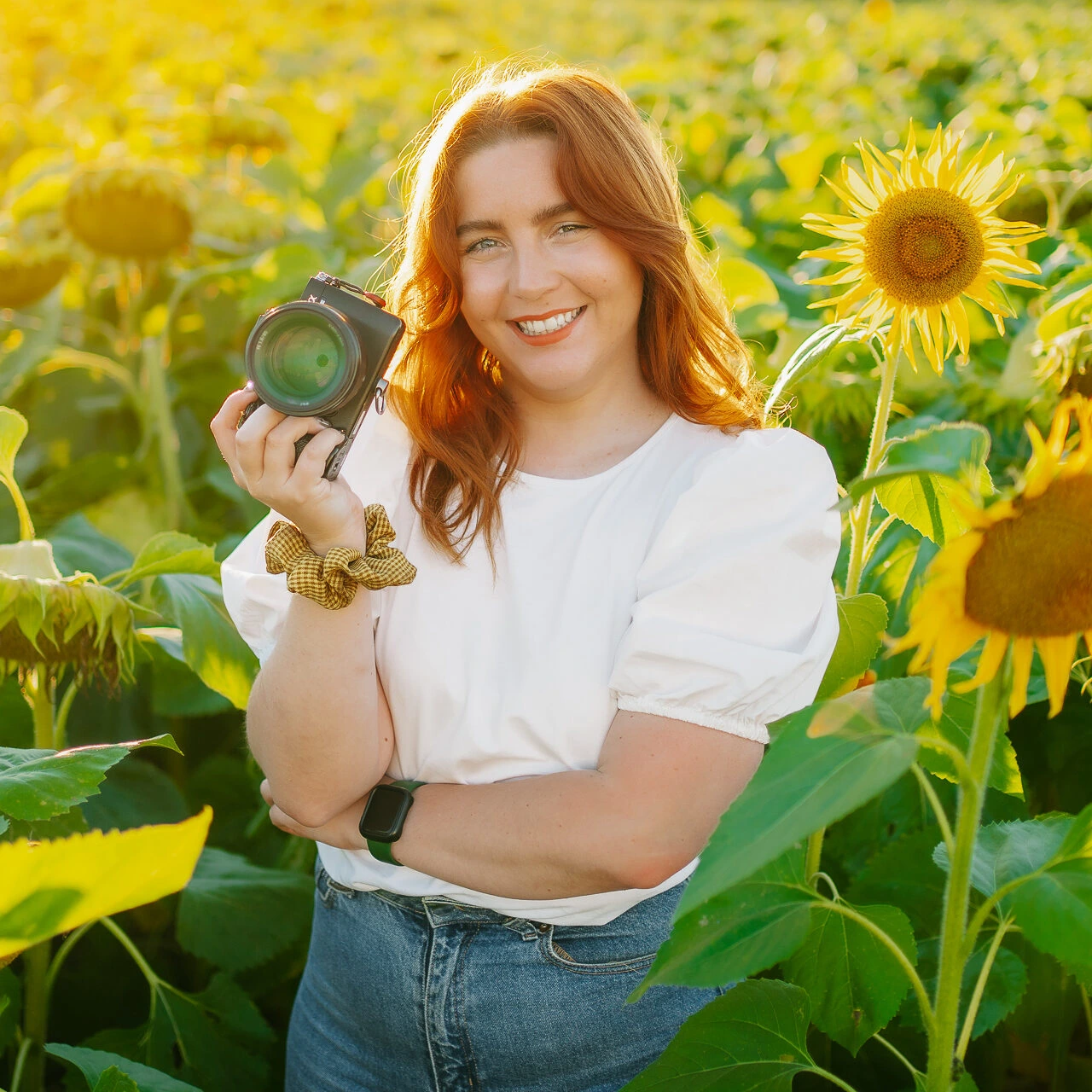 Une femme tenant un appareil photo dans un champ de tournesols.
