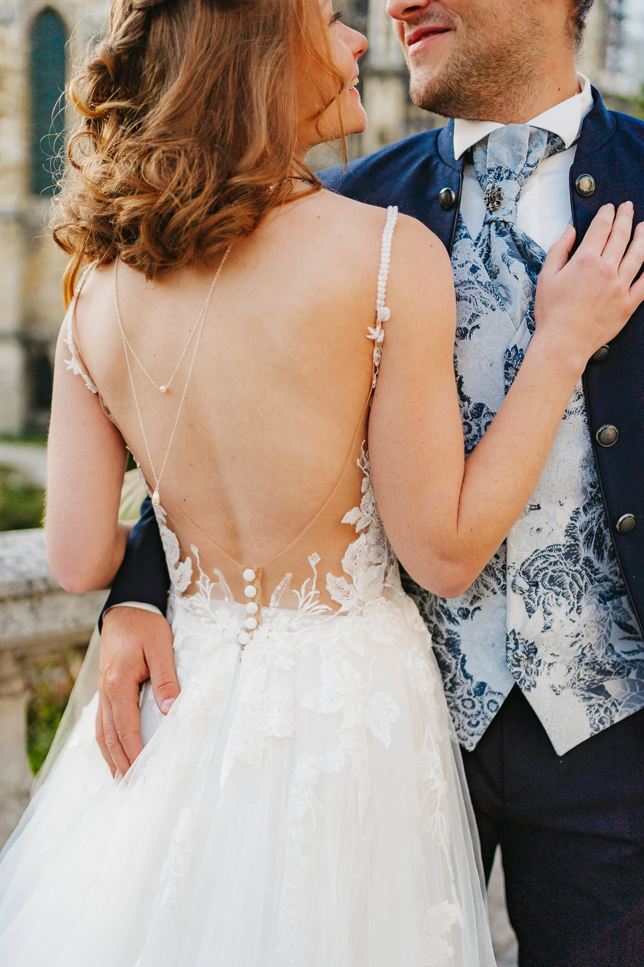 Mariée en robe de dentelle avec marié en gilet bleu